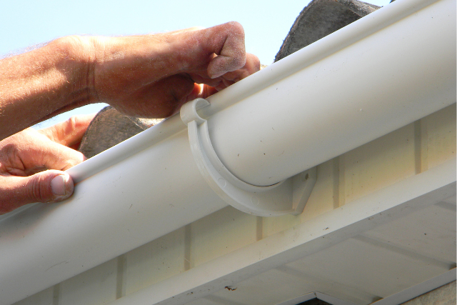 Contractor installing plastic roof gutter