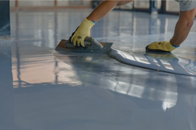 Worker applies gray epoxy resin to the new floor